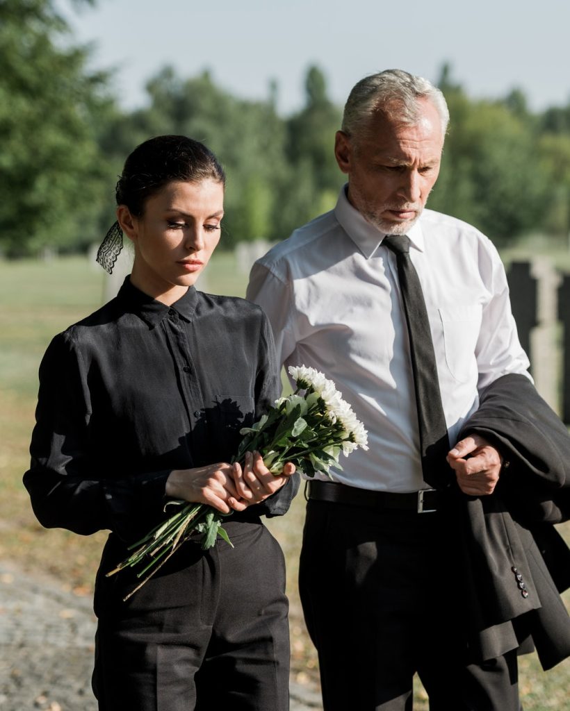 bearded-senior-man-walking-near-woman-with-flowers-on-funeral.jpg